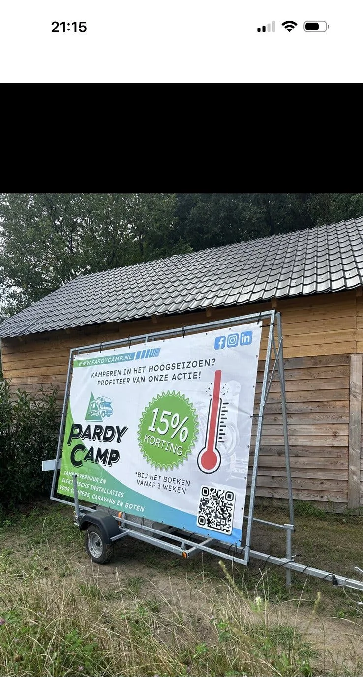 Reclameaanhangwagen in gebruik langs de weg, met een bedrukt reclamedoek in het frame